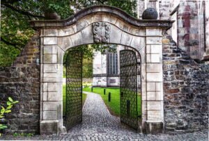  a wrought iron main gate between stone pillars with climbing roses.