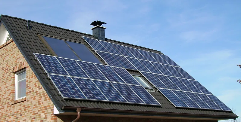 Stylish home exterior with solar panels integrated into modern roof design and decorative landscaping